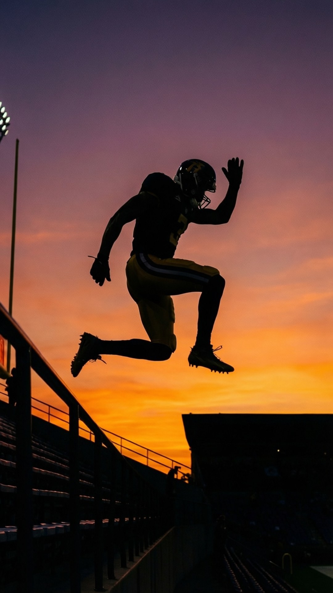 Sunset Leap 壁紙 — 一名足球員在體育場上空以剪影姿態躍起，襯托著充滿活力的日落天空。