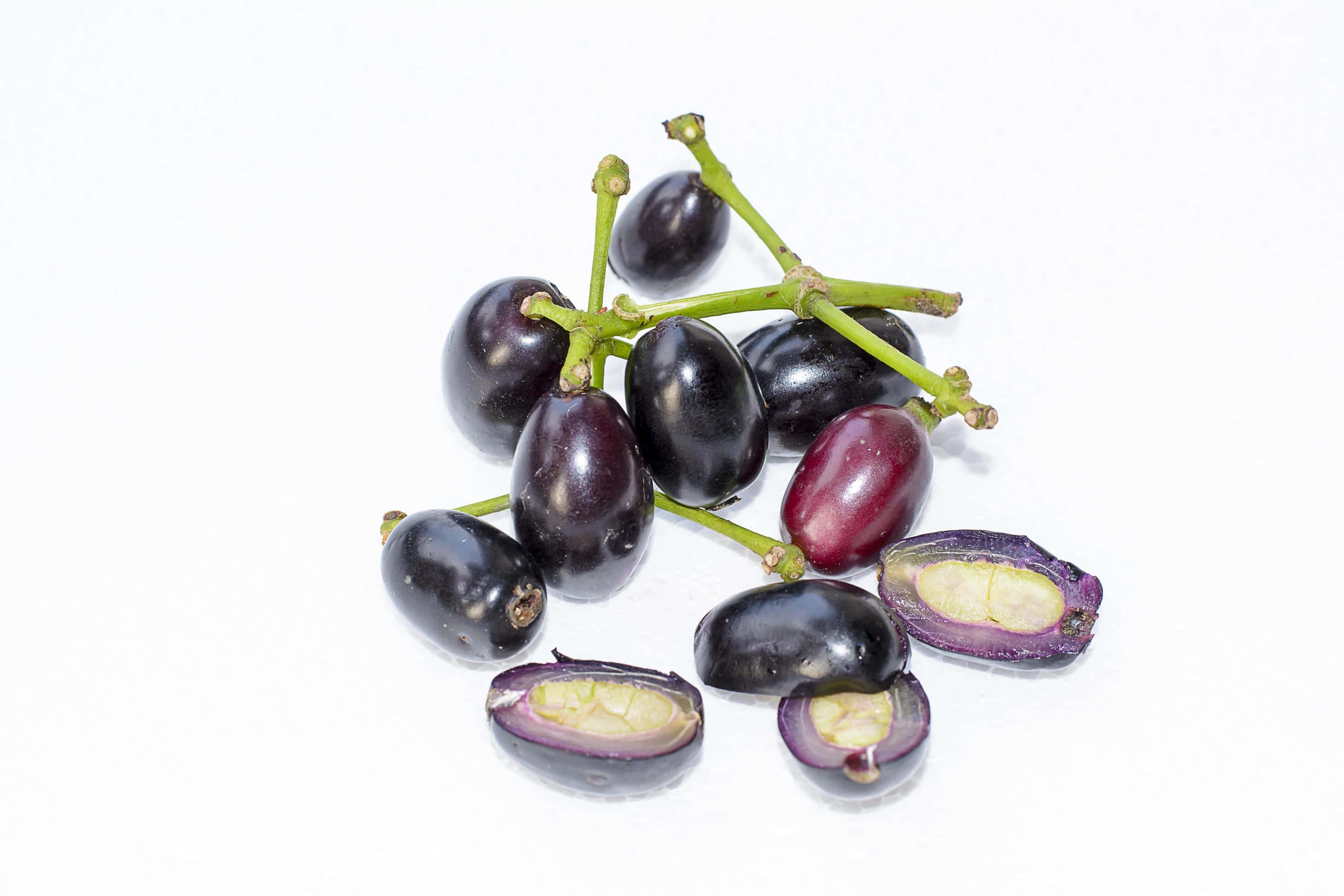 Plum 桌布 壁紙 — 一串光澤深紫色葡萄，帶綠色莖，切半露出淡黃色種子，背景為純白色。