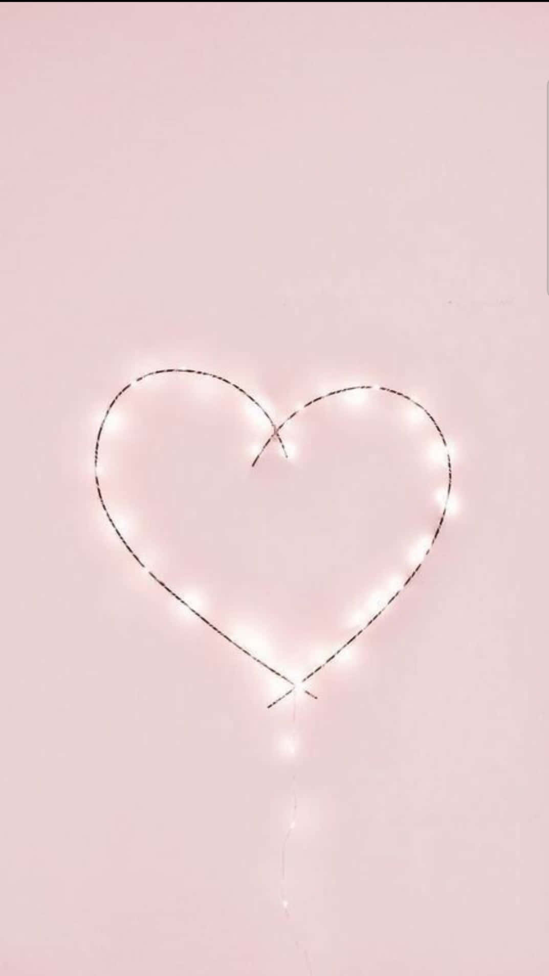 Aesthetic Heart 桌布 壁紙 — 一串發光的白色仙女燈在柔和的粉紅色背景上形成心形。