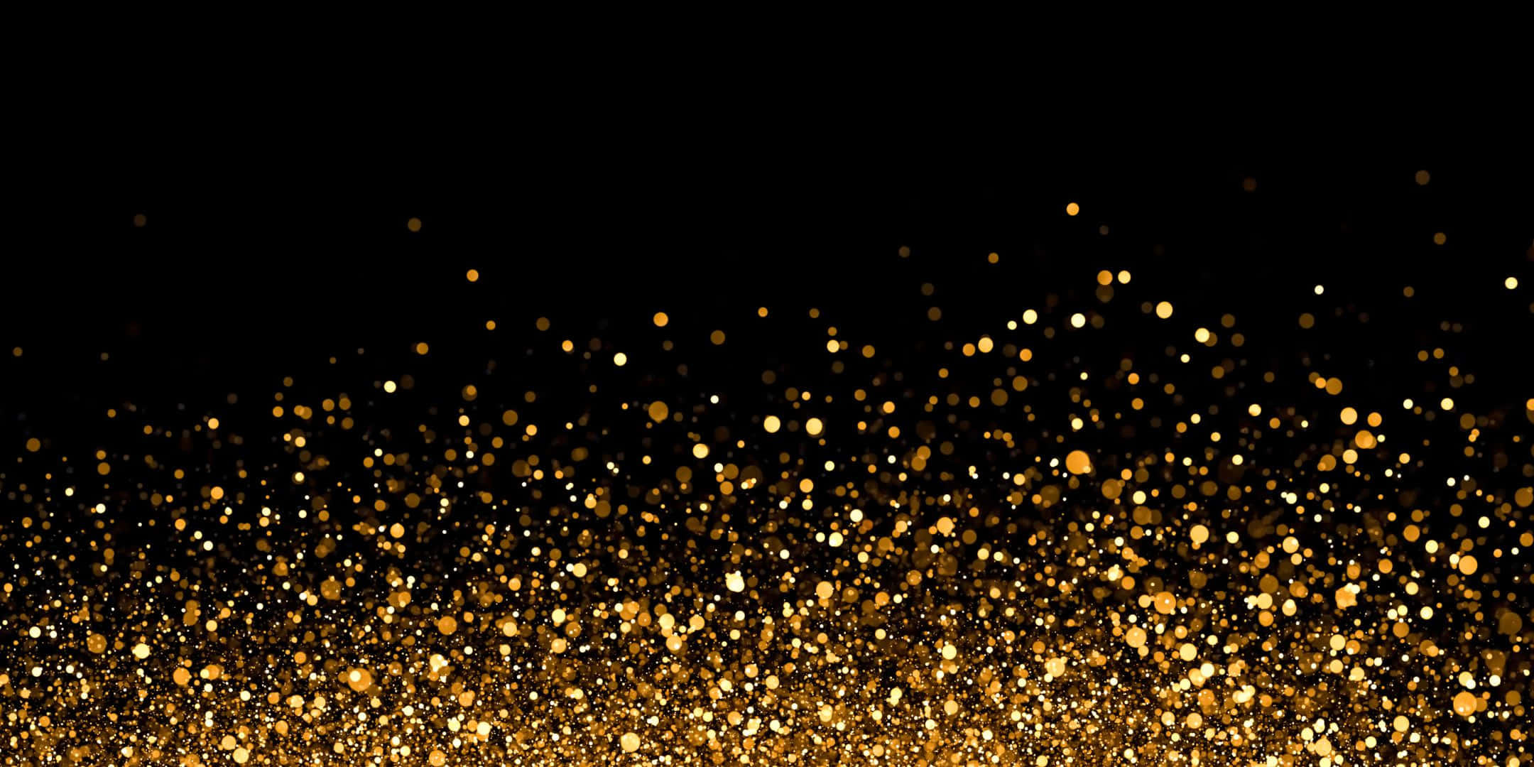 Shimmer 桌布 壁紙 — 一串閃爍的金色亮粉粒子在深黑色背景上漂浮，營造出奢華閃亮的效果。
