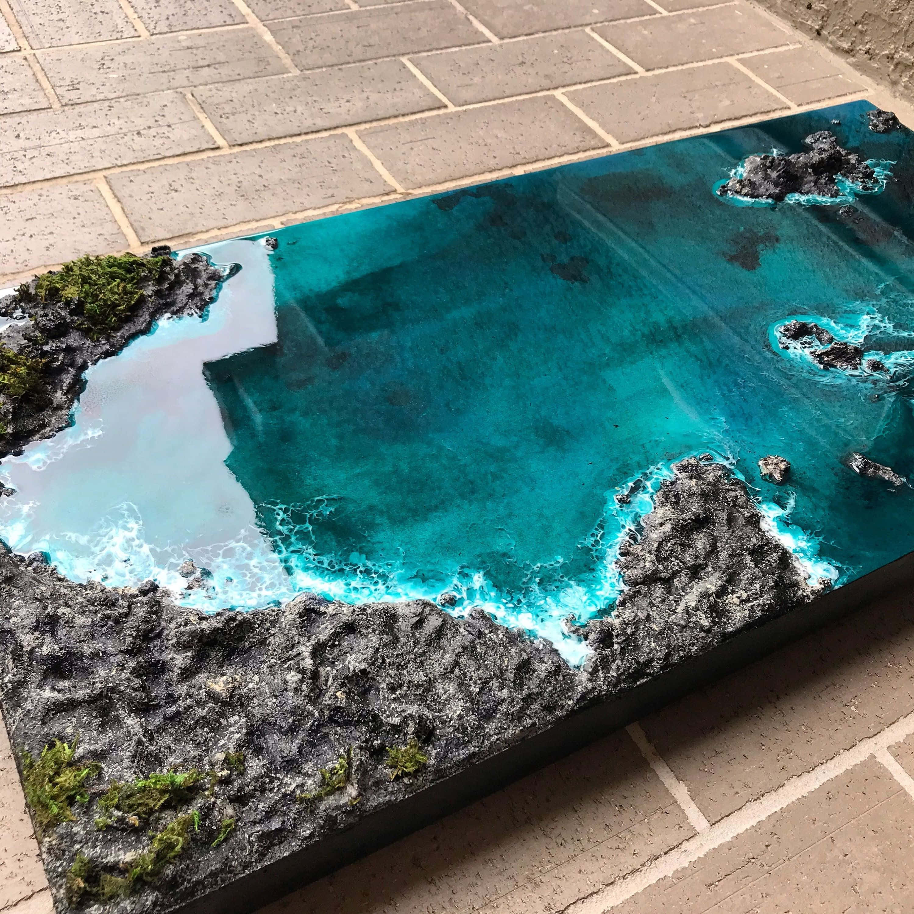 3d Ocean 桌布 壁紙 — 一件令人驚嘆的3D樹脂藝術品，描繪了充滿活力的碧綠海洋，海浪拍打著崎嶇的黑色火山岩和一片片綠色苔蘚。
