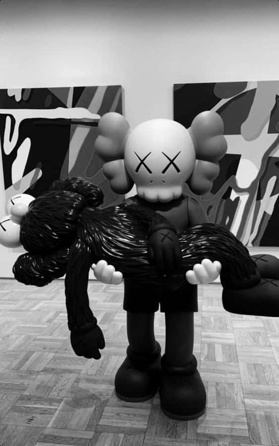 kaws pc 桌布 壁紙 — 一件單色KAWS雕塑手持一個黑色人偶，站立在牆上掛有抽象藝術品的畫廊中。