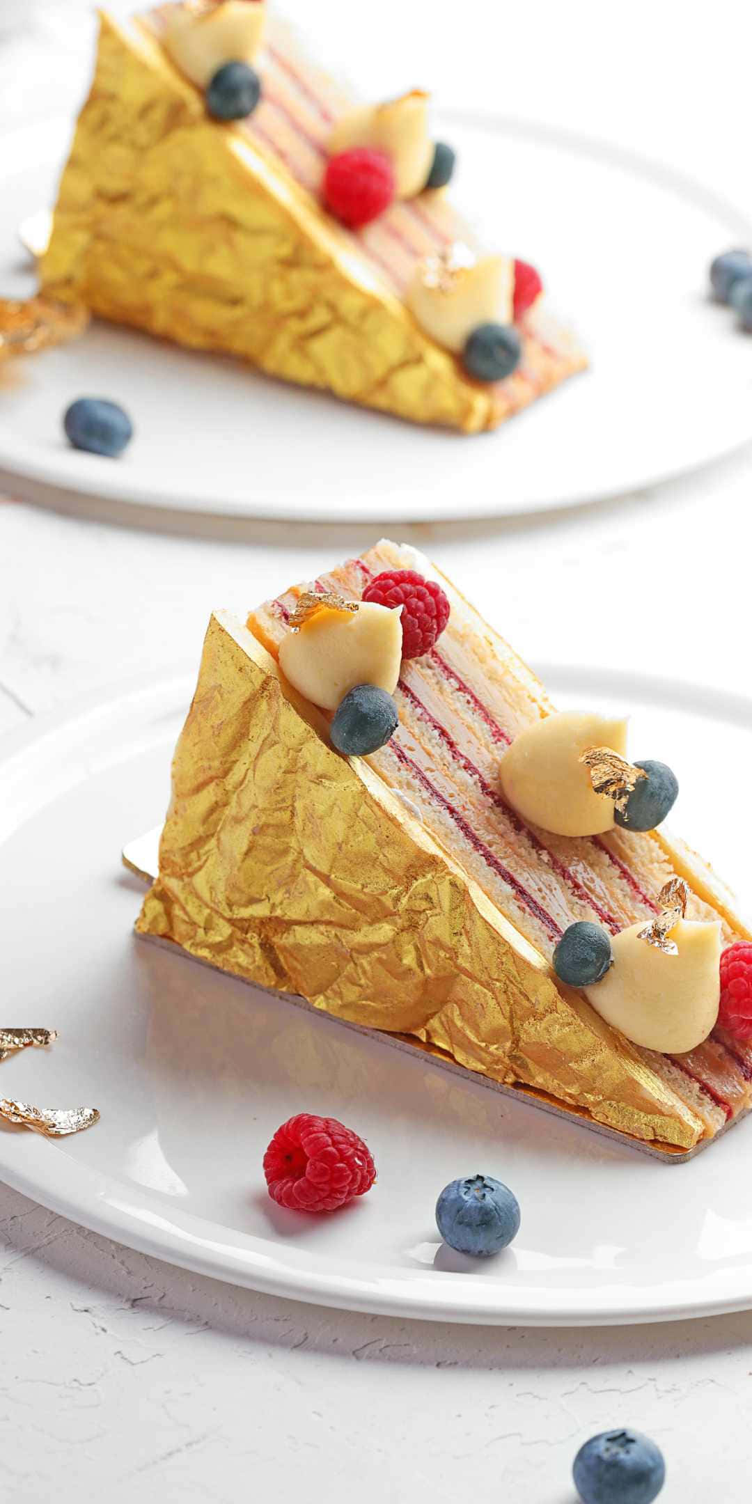 Pastry 桌布 壁紙 — 一件奢華的多層蛋糕，飾有金箔和新鮮漿果，優雅地放在白色盤子上。
