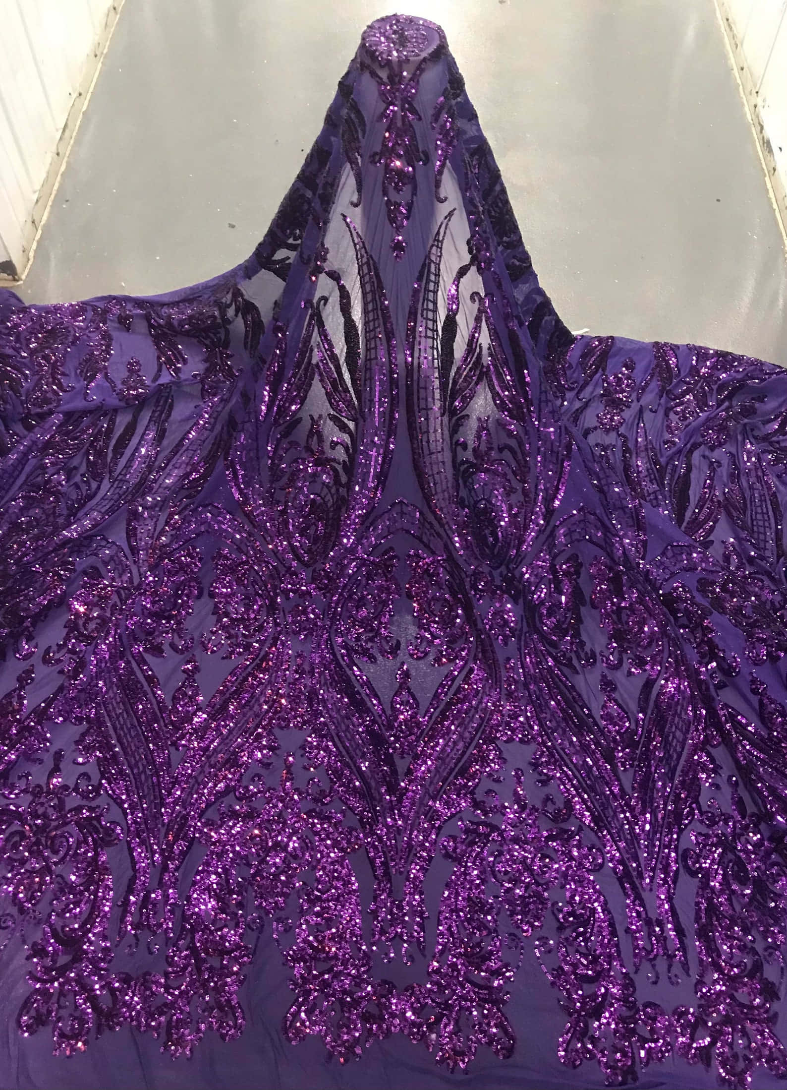 Purple Sequins 桌布 壁紙 — 一件奢華的深紫色長裙，帶有精緻閃爍的花卉刺繡和透明蕾絲細節，鋪展在反光的地板上。