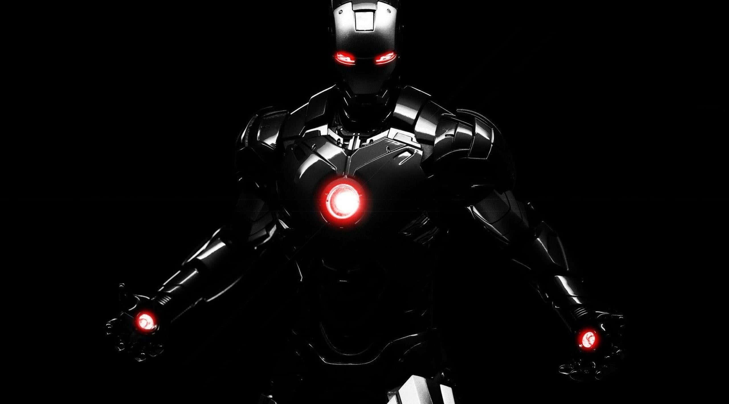 Iron Man Suit 桌布 壁紙 — 一件帶有發光紅眼、胸甲和護手的黑色裝甲服，站在漆黑背景前，氣勢逼人。