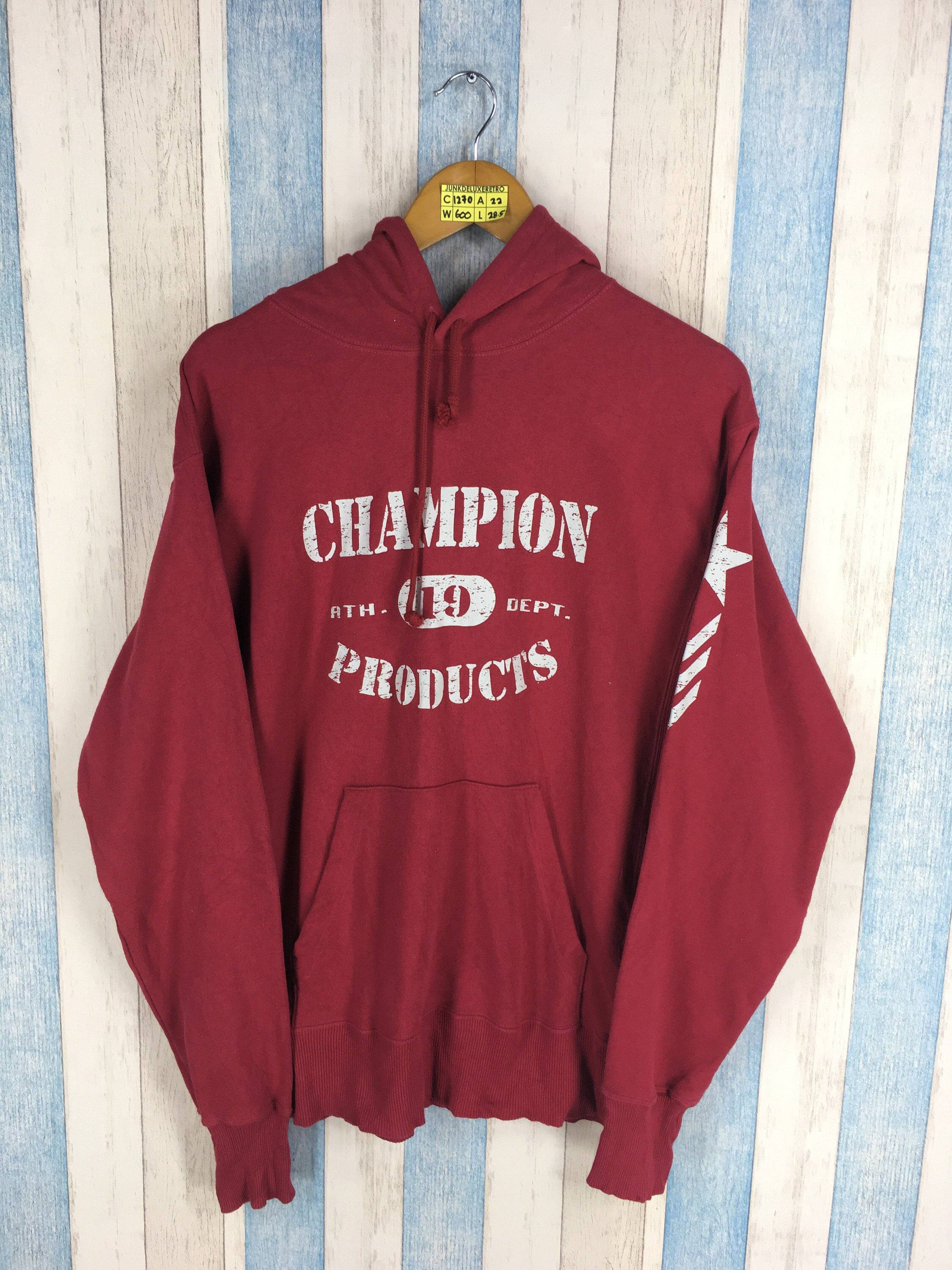 Champion 桌布 壁紙 — 一件復古酒紅色Champion連帽衫，帶白色標誌，掛在木衣架上，背景是藍白條紋木牆。