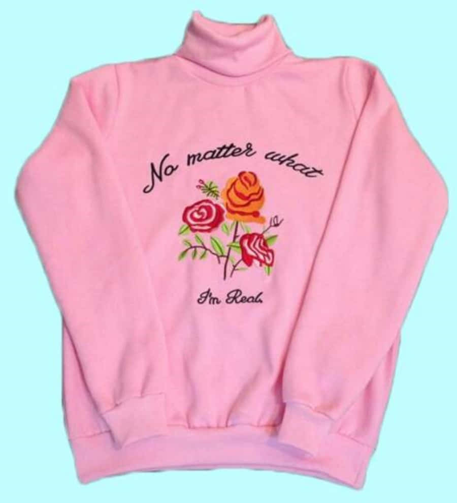 Pink Sweater 桌布 壁紙 — 一件柔軟的粉紅色高領衛衣，繡有玫瑰圖案和「No matter what I'm Real」字句，背景為淺藍色。