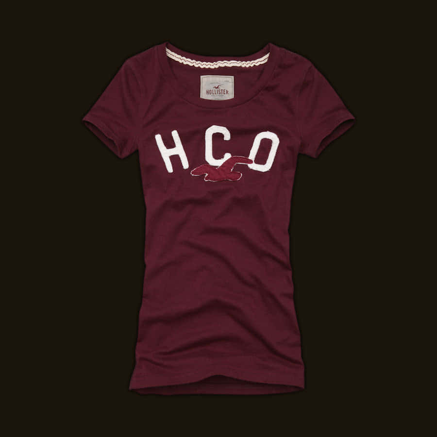 hollister 桌布 壁紙 — 一件栗色Hollister T恤，帶有白色HCO標誌和紅色鳥圖案，背景為深色。