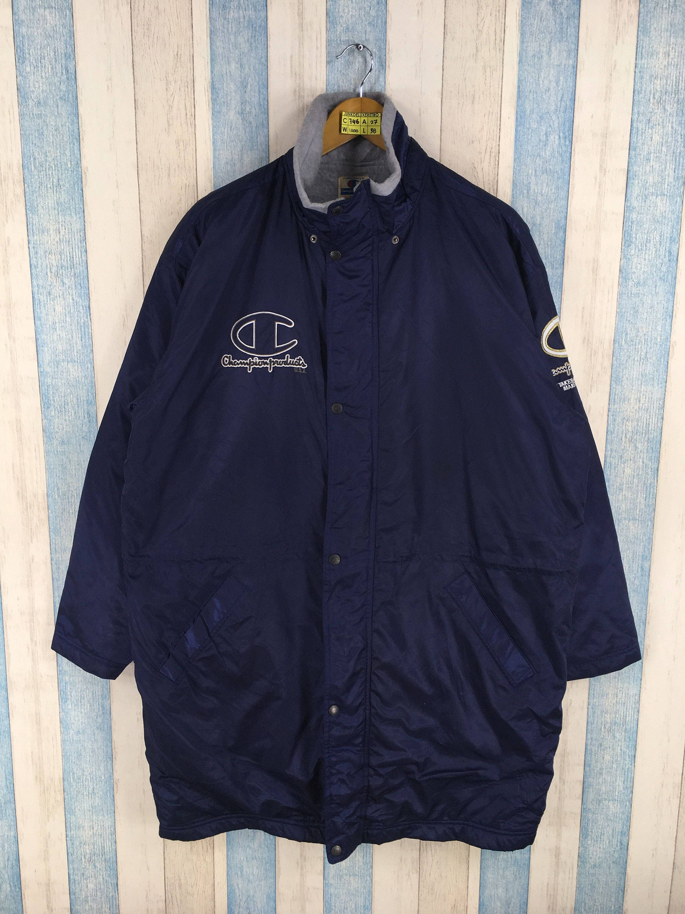 Champion 桌布 壁紙 — 一件海軍藍色的Champion防風外套掛在衣架上，背景是藍白條紋的木牆。