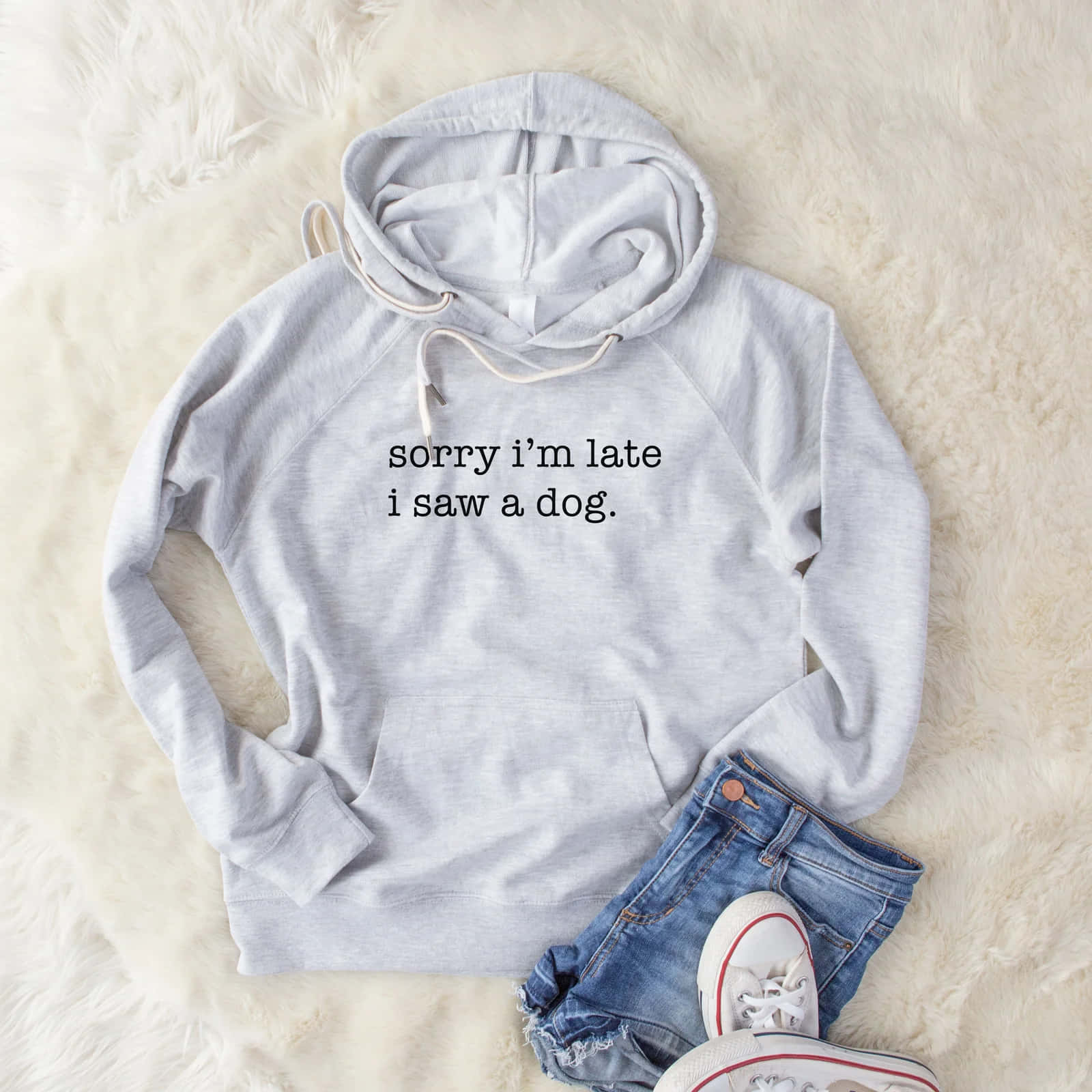 Im Sorry 桌布 壁紙 — 一件淺灰色連帽上衣，上面印有「sorry i'm late i saw a dog」字樣，放在毛絨白色地毯上，旁邊有牛仔短褲和白色運動鞋。