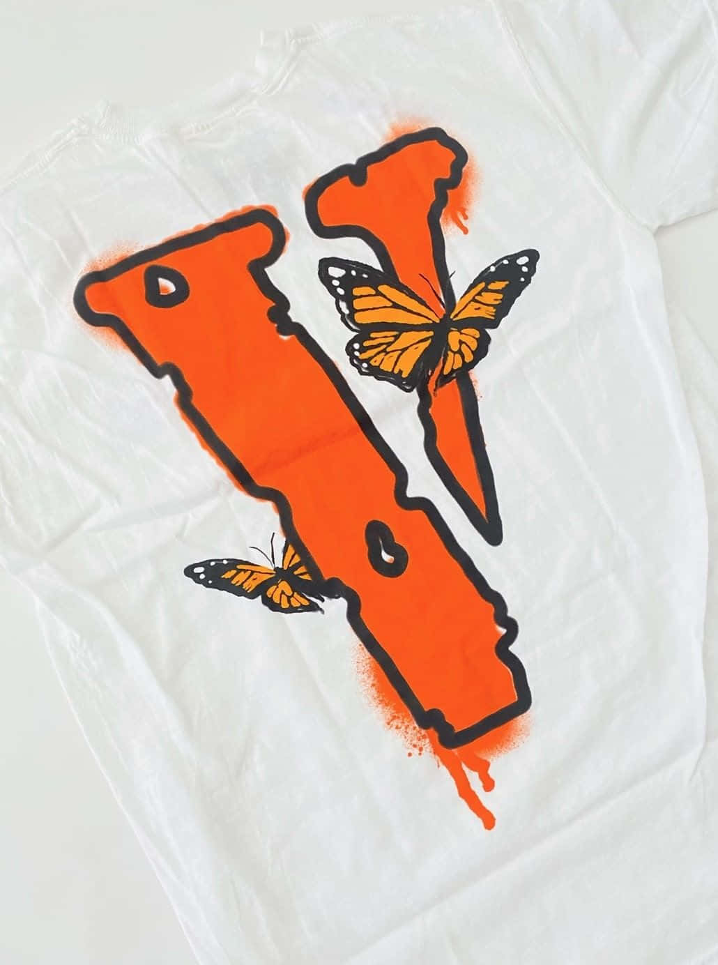 Vlone 桌布 壁紙 — 一件白色T恤上有一個大膽的橙色噴漆字母V，帶有黑色輪廓，兩隻帝王蝶棲息在上面。