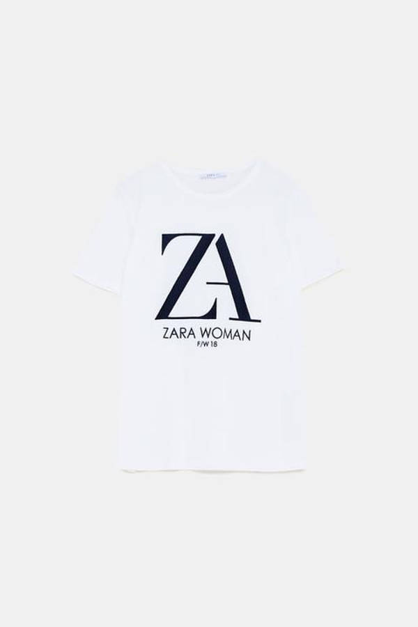 Zara 桌布 壁紙 — 一件純白T恤，上面印有醒目的黑色ZARA WOMAN F/W 18標誌，背景為簡潔的淺色背景。