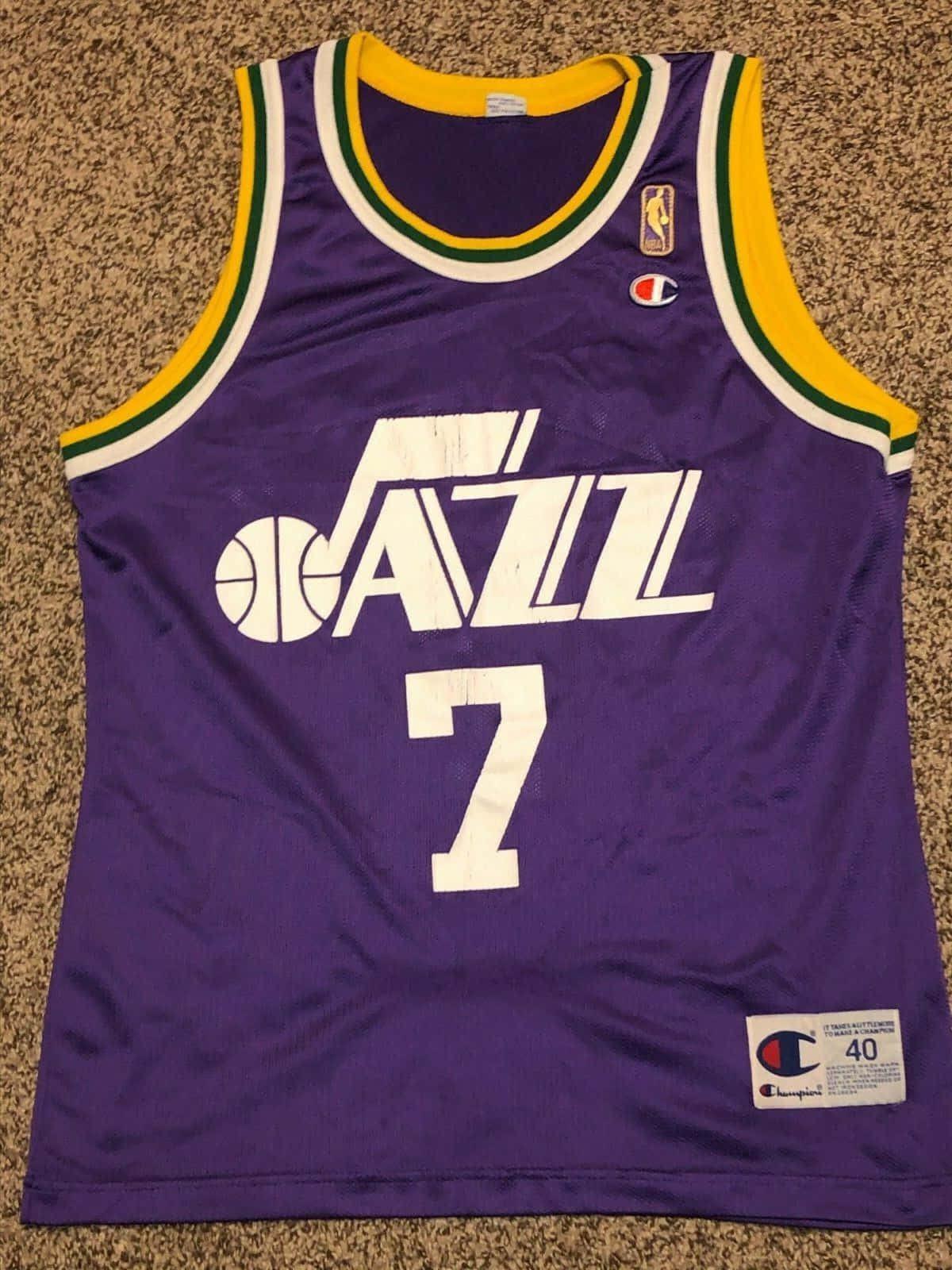 NBA 桌布 壁紙 — 一件紫色猶他爵士籃球球衣，帶有白色7號和黃綠色飾邊，平放在棕色地毯上。
