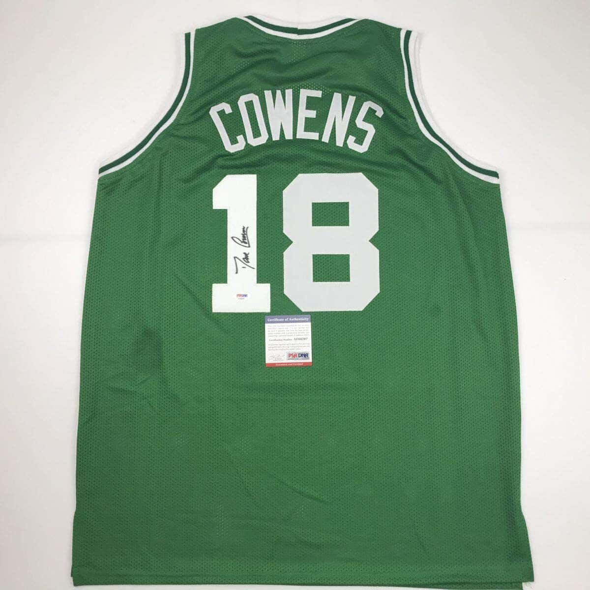 NBA 桌布 壁紙 — 一件綠色波士頓塞爾提克球衣，印有白色 'COWENS' 及號碼 '18'，已簽名並認證，平放在白色表面上。