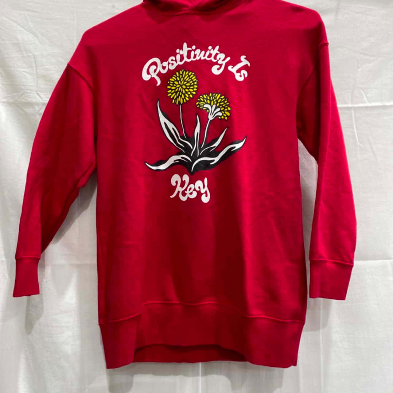 Red Hoodie 桌布 壁紙 — 一件鮮紅色連帽上衣，白色背景上印有蒲公英的白色圖案和「Positivity Is Key」字句。