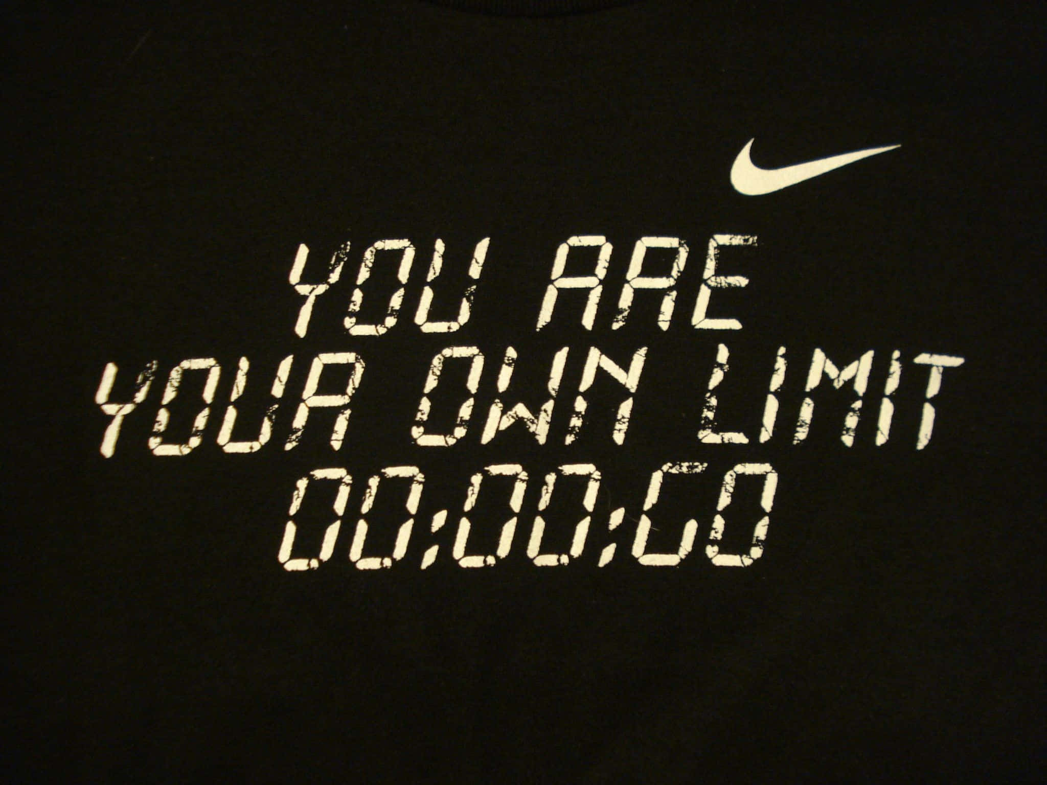 動力 桌布 壁紙 — 一件黑色T恤上印有「YOU ARE YOUR OWN LIMIT」的磨損白色字樣，上方有一個顯示00:00:00的數位計時器，並帶有Nike勾勾標誌。