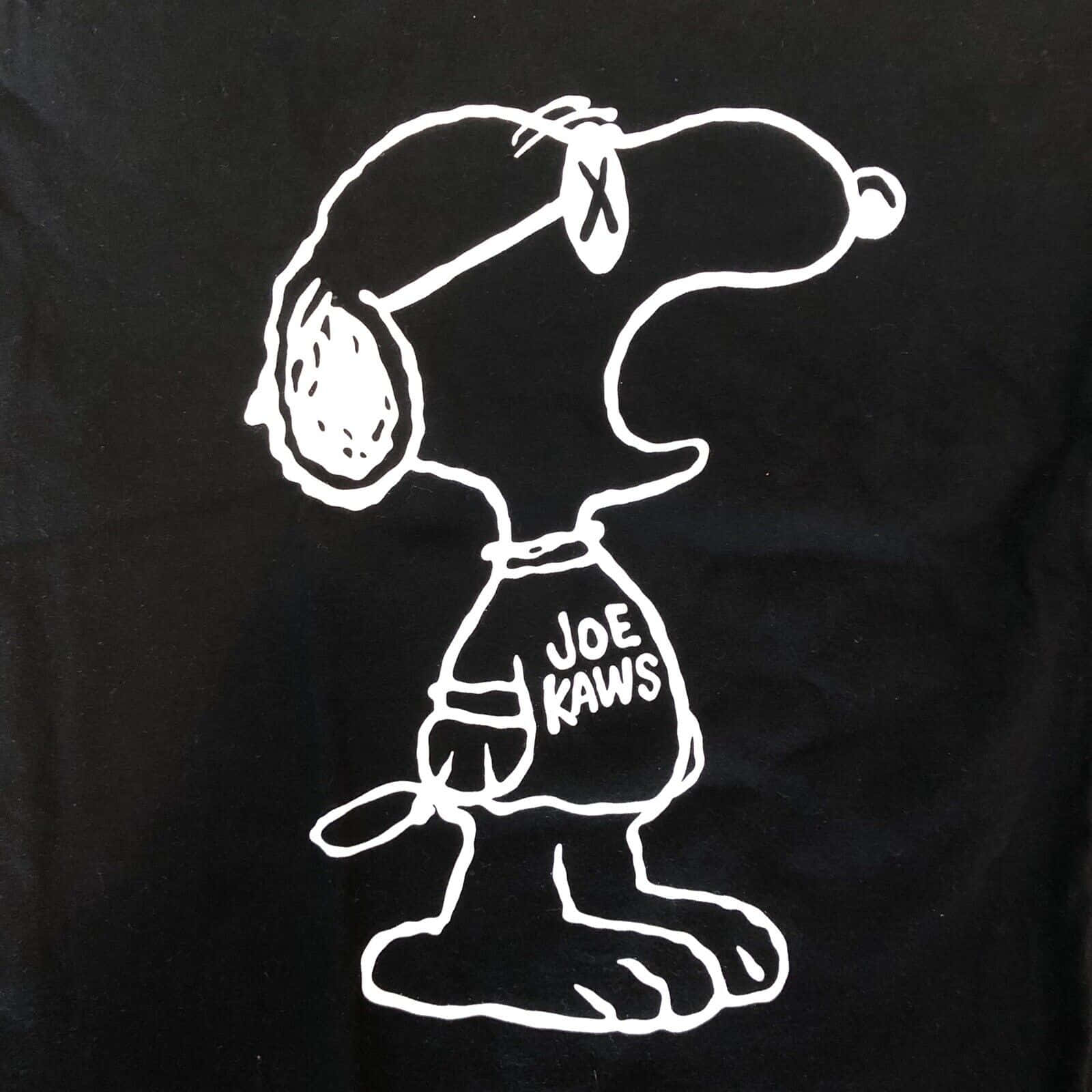 Kaws Snoopy 桌布 壁紙 — 一件黑色T恤上印有史努比戴著帶有X標誌的帽子、身穿寫著Joe Kaws的襯衫的醒目白色輪廓。
