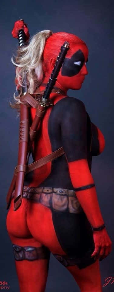 Lady Deadpool 桌布 壁紙 — 一位Cosplayer穿著紅黑色死侍服裝，背上背著劍，在黑暗的攝影棚背景下側面擺姿勢。