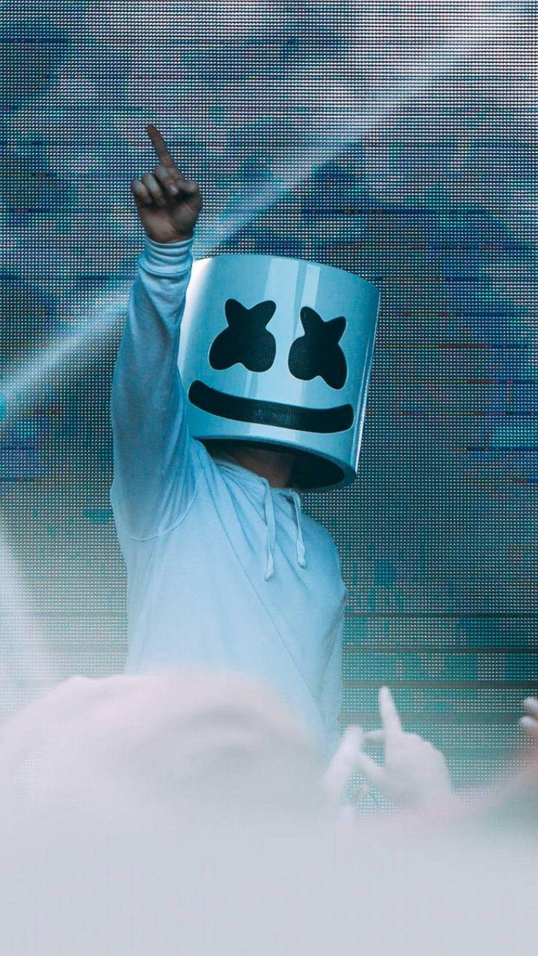 marshmello iPhone 桌布 壁紙 — 一位DJ戴著標誌性的白色頭盔，黑色X眼睛，在發光的數位螢幕背景下向上指。