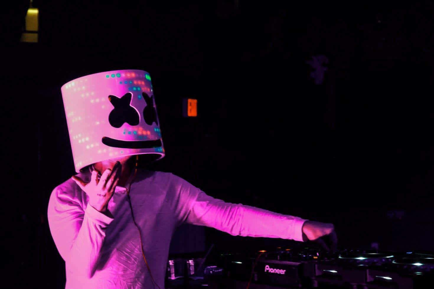 Marshmello 動態圖 桌布 壁紙 — 一位DJ戴著發光的粉紅色棉花糖頭盔，在黑暗的夜店中於霓虹燈下混音。