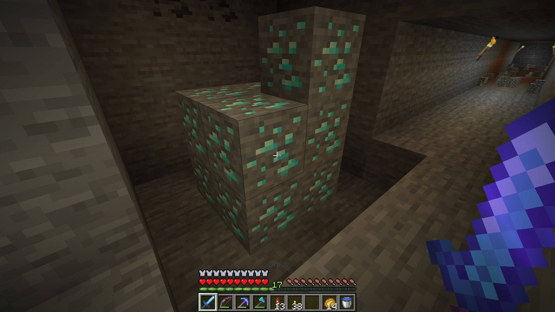 我的世界 鑽石 桌布 壁紙 — 一位Minecraft玩家在昏暗的地下洞穴中，手持一把鑽石劍，旁邊有發光的綠色鑽石礦石方塊。