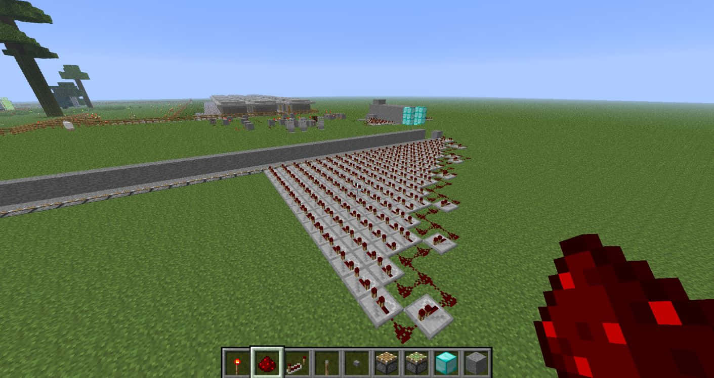 Minecraft Redstone 桌布 壁紙 — 一位Minecraft玩家手持紅石火炬，站在草地上石板上的大型紅石火炬網格旁。
