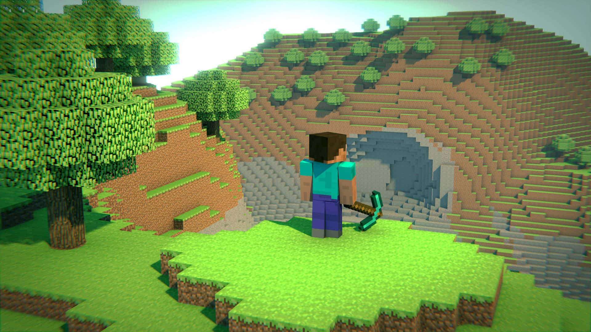 Minecraft Survival 桌布 壁紙 — 一位Minecraft玩家站在洞穴入口前，背景是方塊像素風景，有綠樹和起伏的山丘，天空明亮。