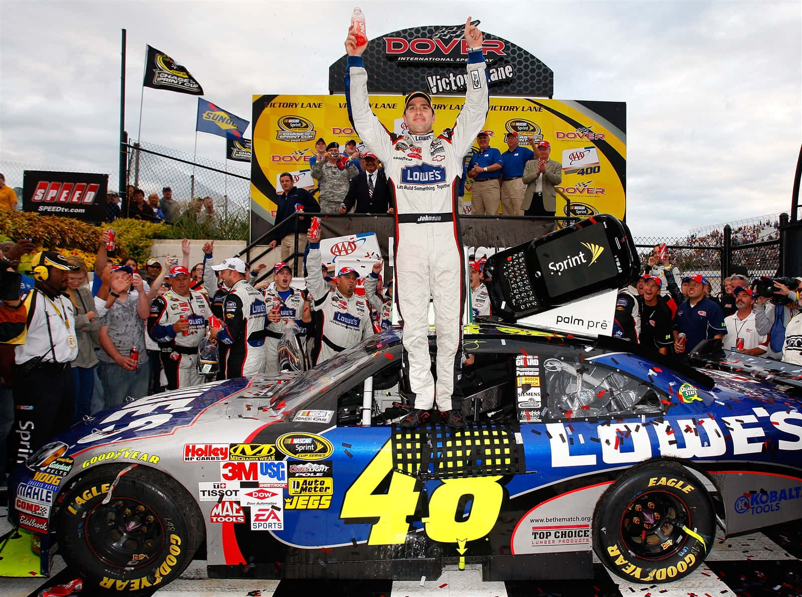 Jimmie Johnson 桌布 壁紙 — 一位NASCAR車手在Dover International Speedway的賽車上高舉雙臂慶祝勝利，五彩紙屑飄落。