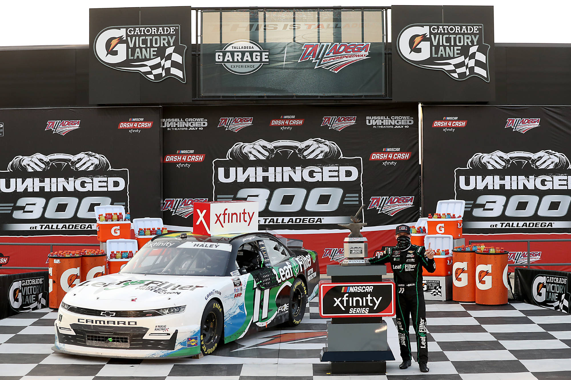 人物 桌布 壁紙 — 一位NASCAR車手在塔拉迪加舉行的Xfinity系列賽中，與他的賽車在方格旗頒獎台上慶祝勝利。
