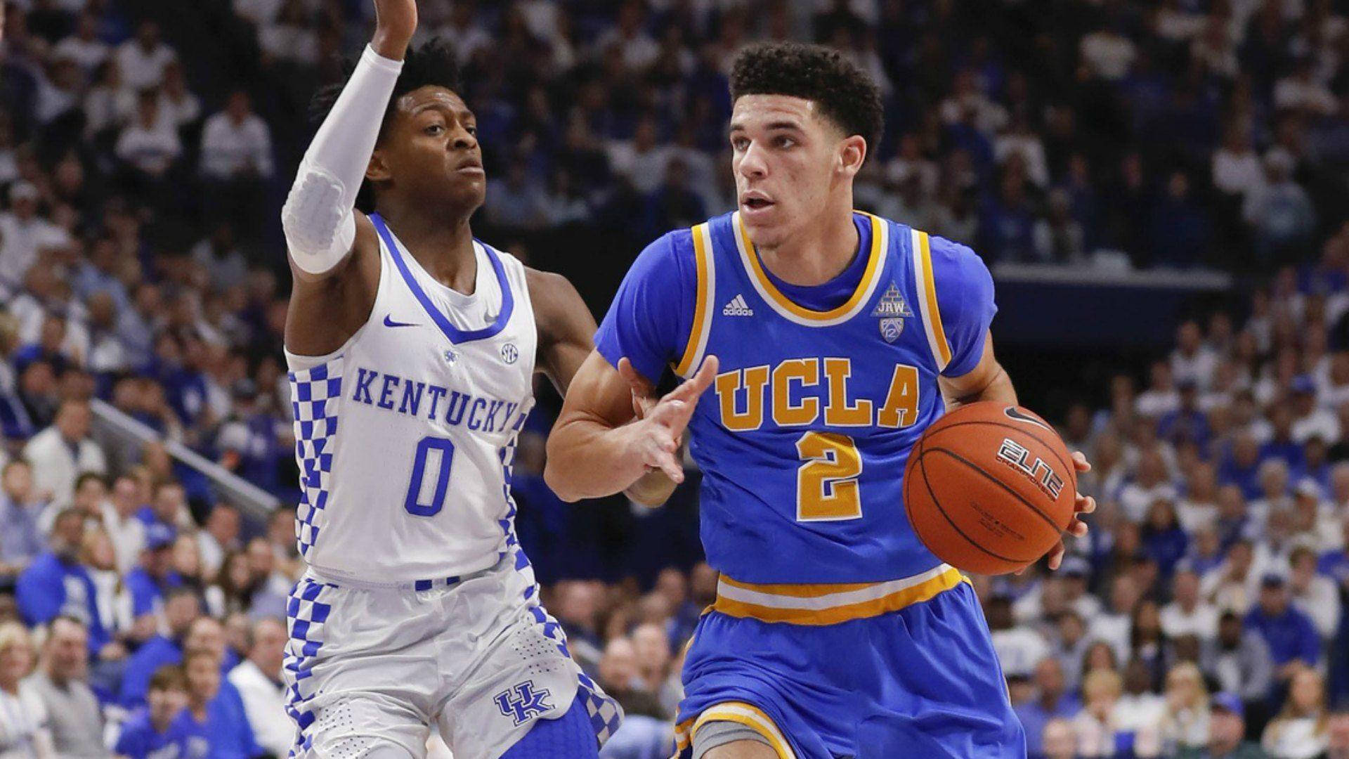 ucla 桌布 壁紙 — 一位UCLA籃球運動員在擠滿觀眾的場館中運球，同時受到肯塔基球員的緊密防守。