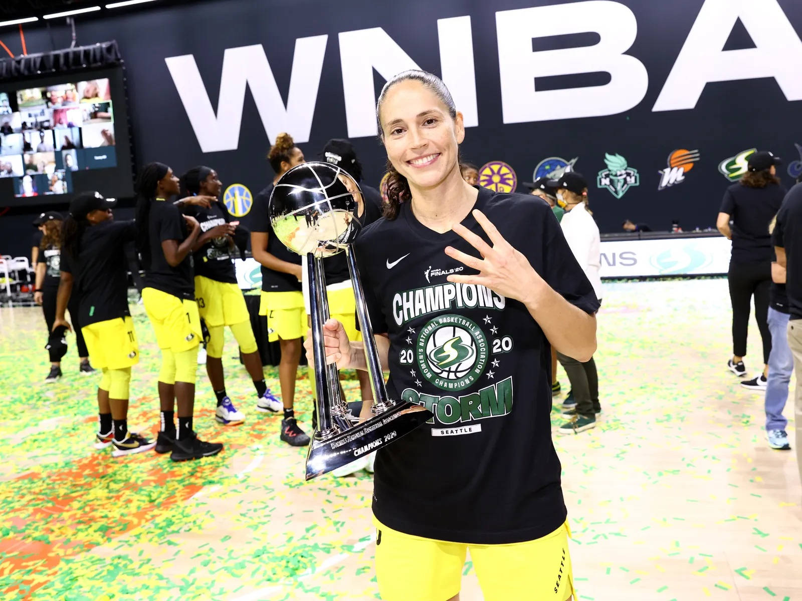 Sue 桌布 壁紙 — 一位WNBA冠軍籃球員在球場上，於五彩紙屑中手持閃閃發光的獎盃，笑容燦爛。