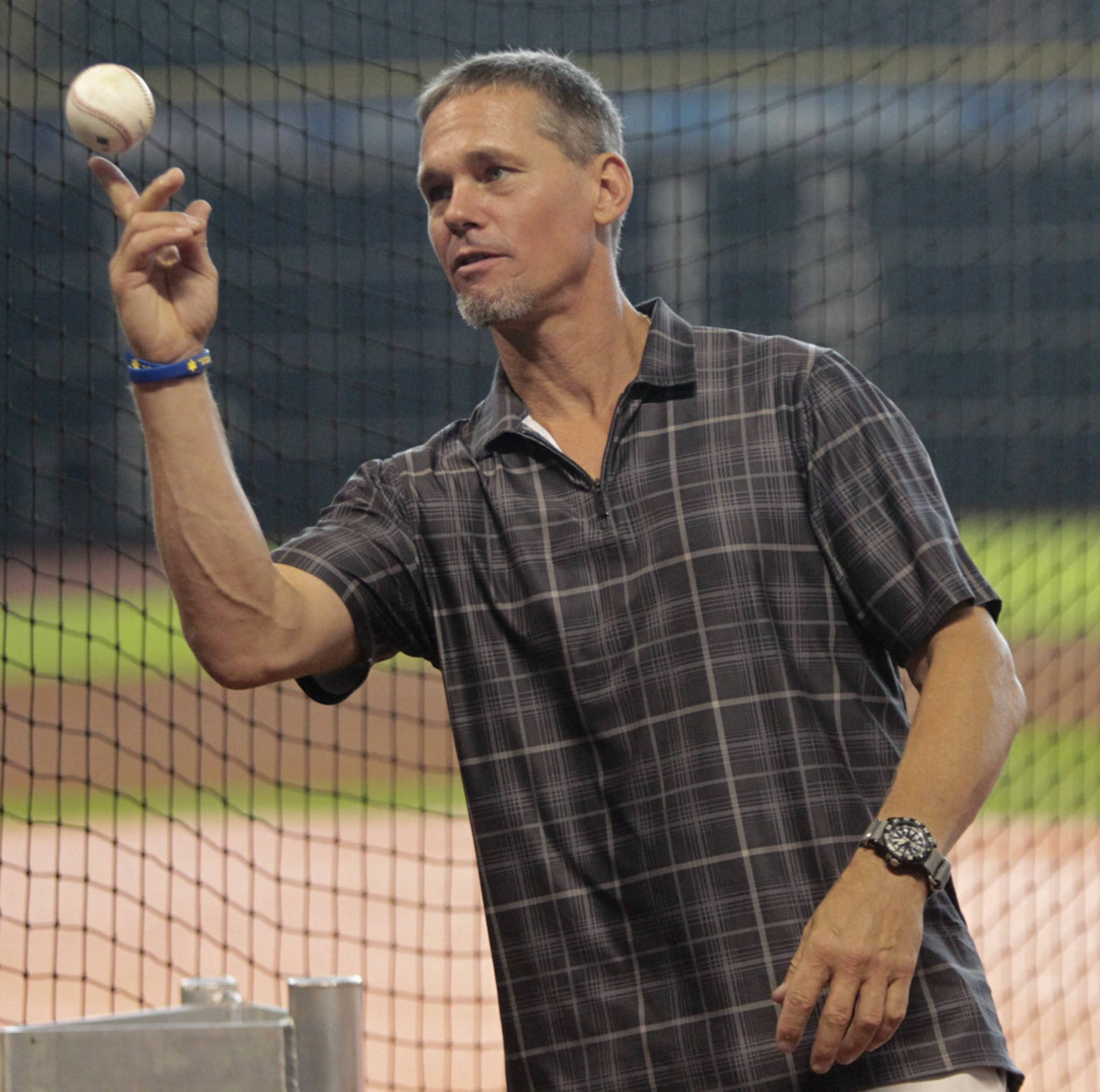 Craig Biggio 桌布 壁紙 — 一位中年男子穿著格紋襯衫，夜晚在打擊籠內用指尖平衡棒球。