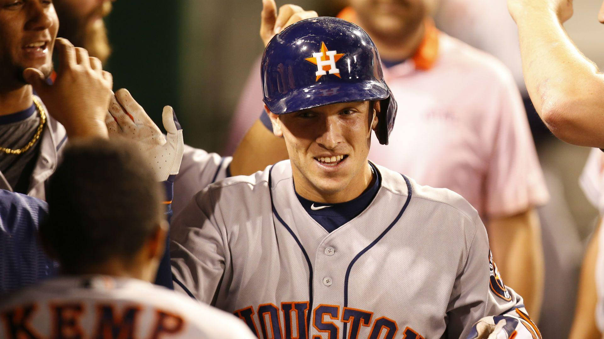 Bregman 桌布 壁紙 — 一位休士頓太空人棒球球員在球場燈光下，於球員休息區慶祝時，隊友與他擊掌，他露出微笑。
