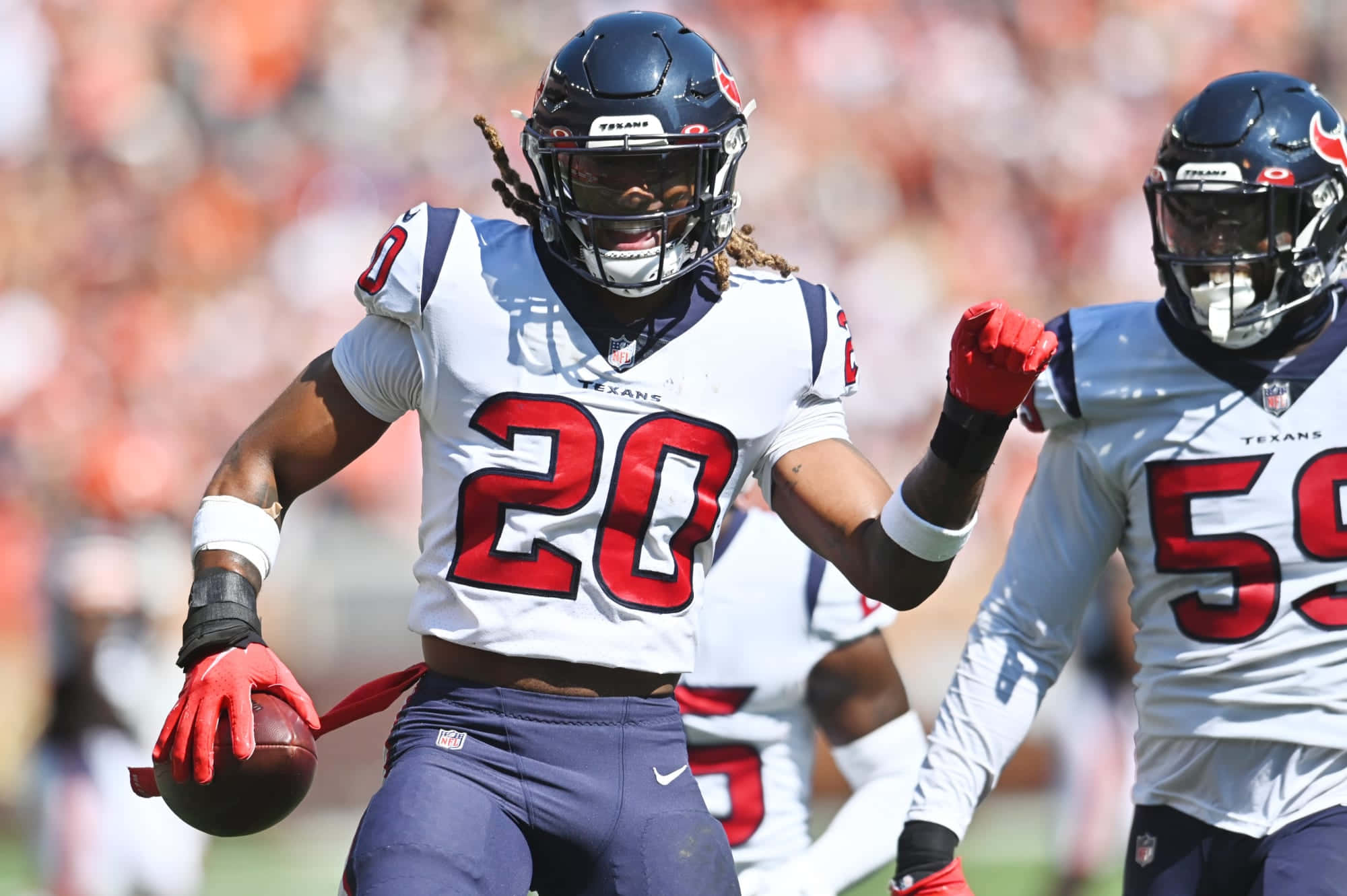 Tyrann Mathieu 桌布 壁紙 — 一位休士頓德州人的美式足球員身穿白色20號球衣，在日間比賽中握緊拳頭慶祝，同時抱著足球。