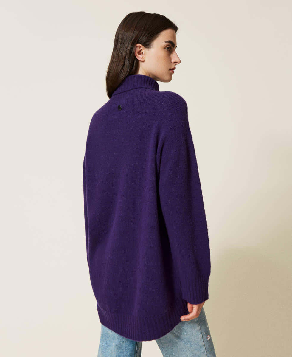Purple Turtle-neck Sweater 桌布 壁紙 — 一位側面女子穿著寬鬆的紫色高領毛衣和藍色牛仔褲，背景為純米色。