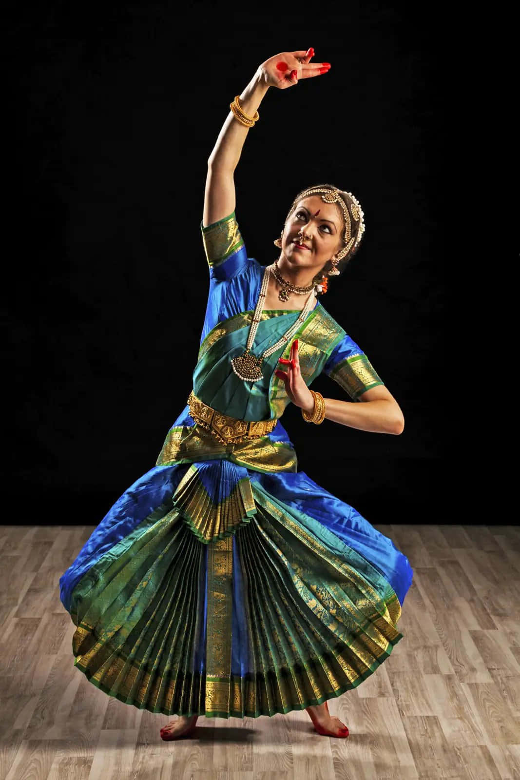 dancer 桌布 壁紙 — 一位優雅的印度古典舞者身穿鮮豔的藍綠色服裝，在純黑背景下擺出沉穩的姿勢。
