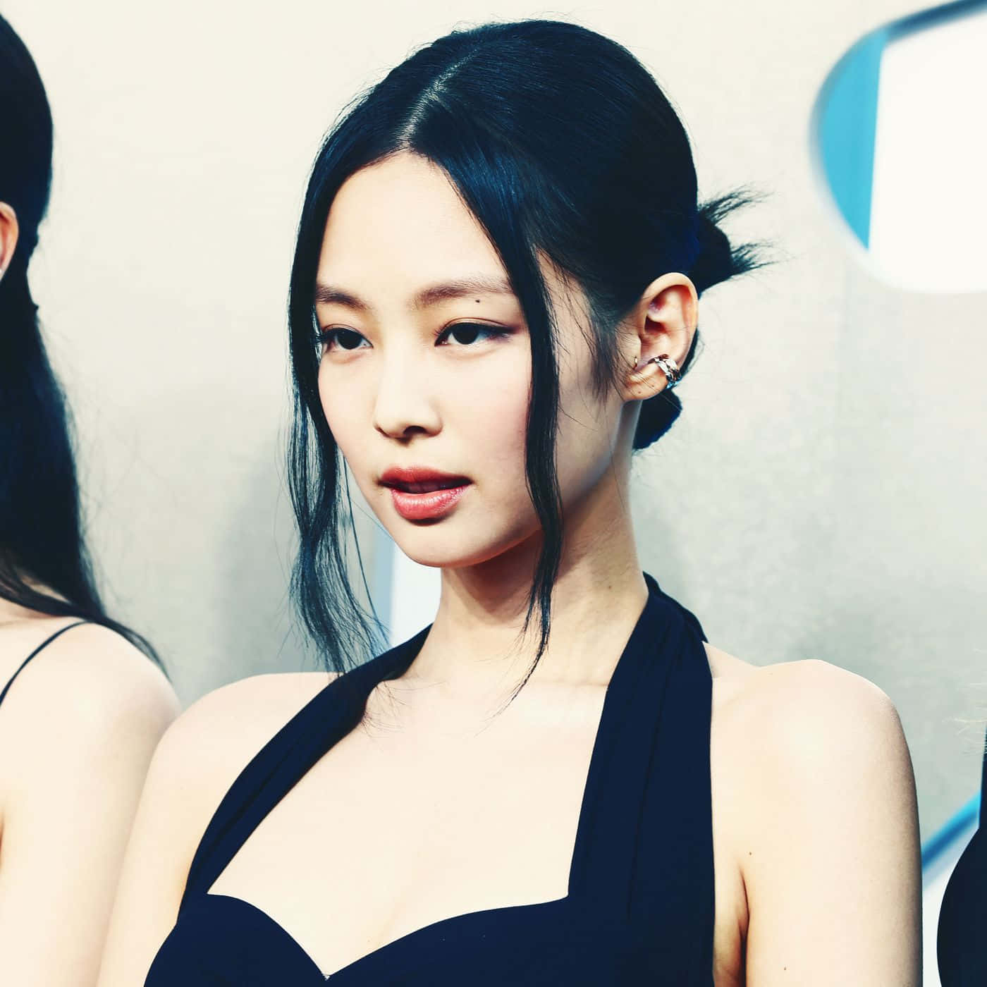 BLACKPINK 桌布 壁紙 — 一位優雅的女人，擁有光滑的黑髮和鮮豔的紅唇，穿著時尚的黑色掛頸連衣裙，背景簡約。