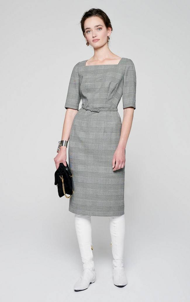 Clothes 桌布 壁紙 — 一位優雅的女士穿著灰色格紋連衣裙和白色靴子，站在純白色背景前，手持黑色手拿包。