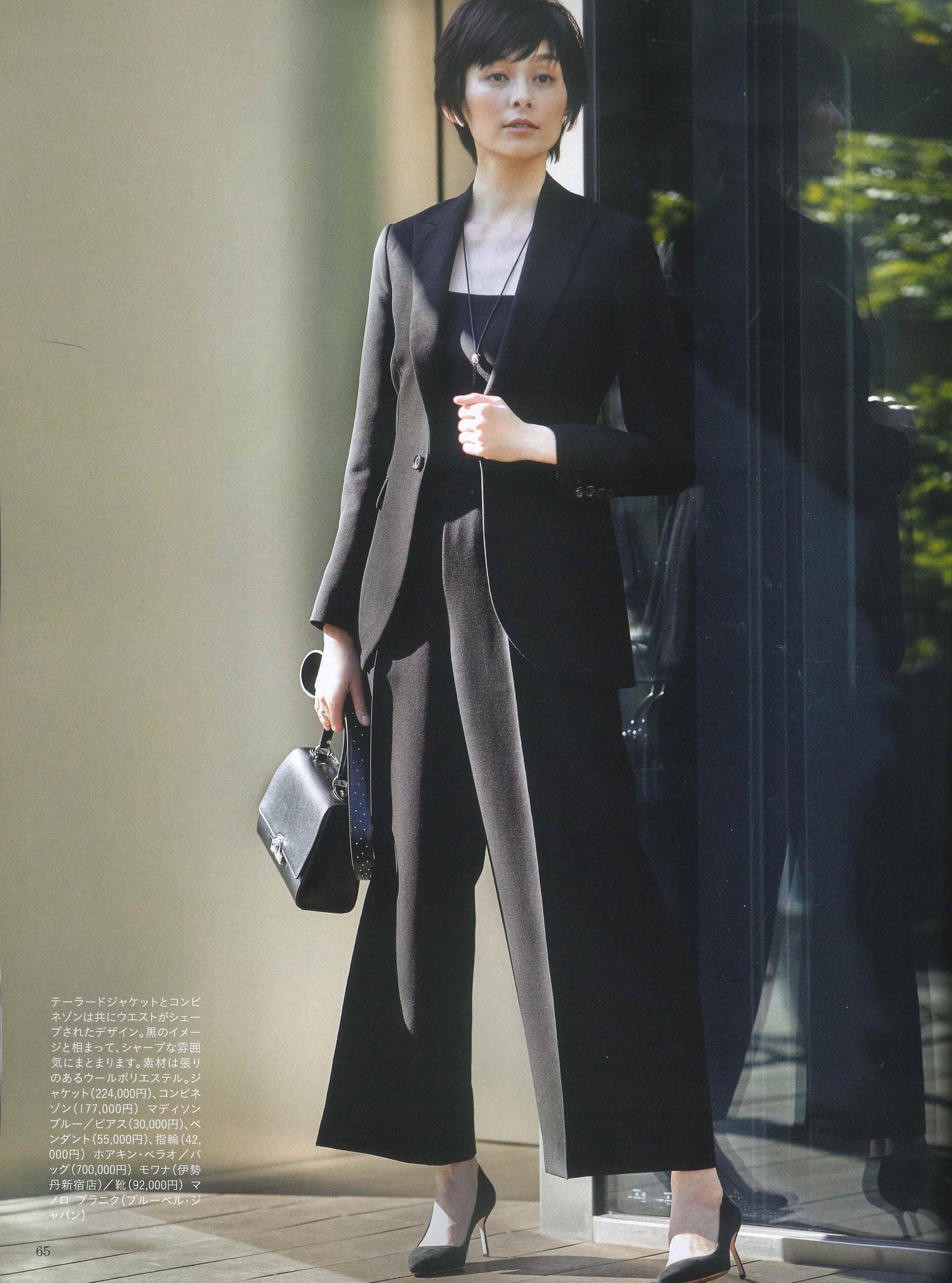 Magazine 桌布 壁紙 — 一位優雅的女士身穿時尚黑色西裝，站在玻璃門旁，身後映照著綠意。