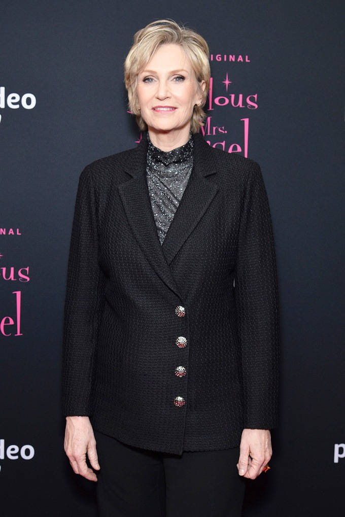 Celebrity 桌布 壁紙 — 一位優雅的金色短髮女性，在推廣活動中穿著帶有裝飾鈕扣的質感黑色西裝外套，內搭閃亮上衣。