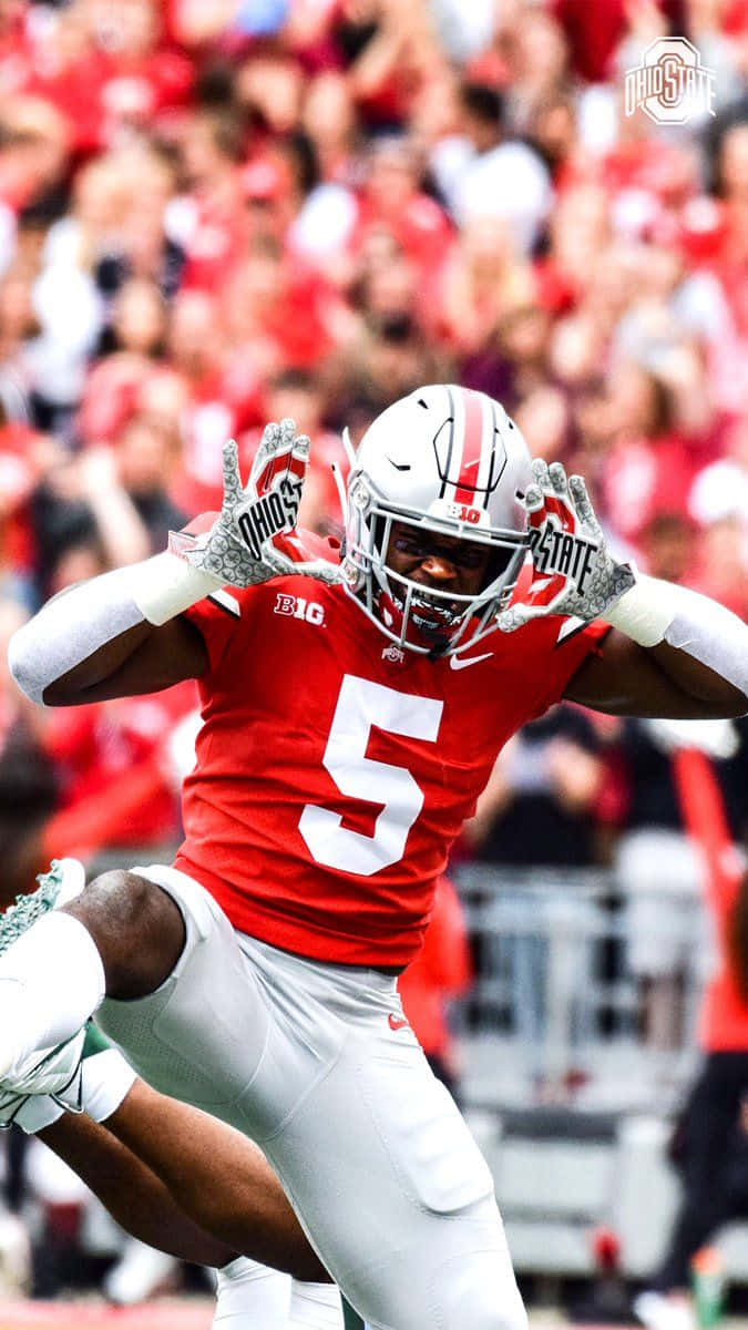 Ohio State iPhone 桌布 壁紙 — 一位充滿活力的俄亥俄州立大學美式足球員，身穿紅白球衣，在日間比賽中雙臂高舉，在空中慶祝。