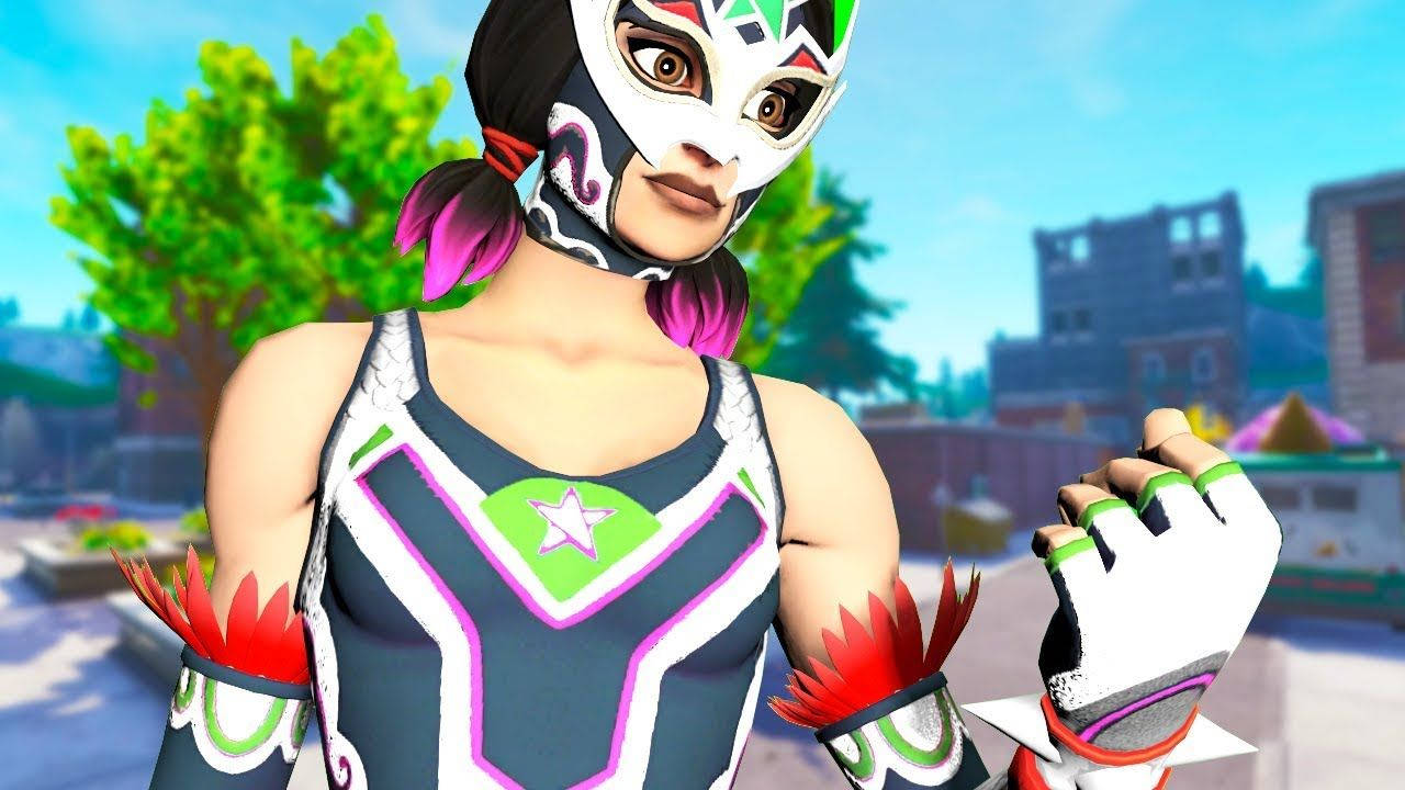 Fortnite 縮圖 桌布 壁紙 — 一位充滿活力的女摔角手，戴著彩色面具，穿著飾有星星的服裝，自信地站在陽光普照的城市環境中。