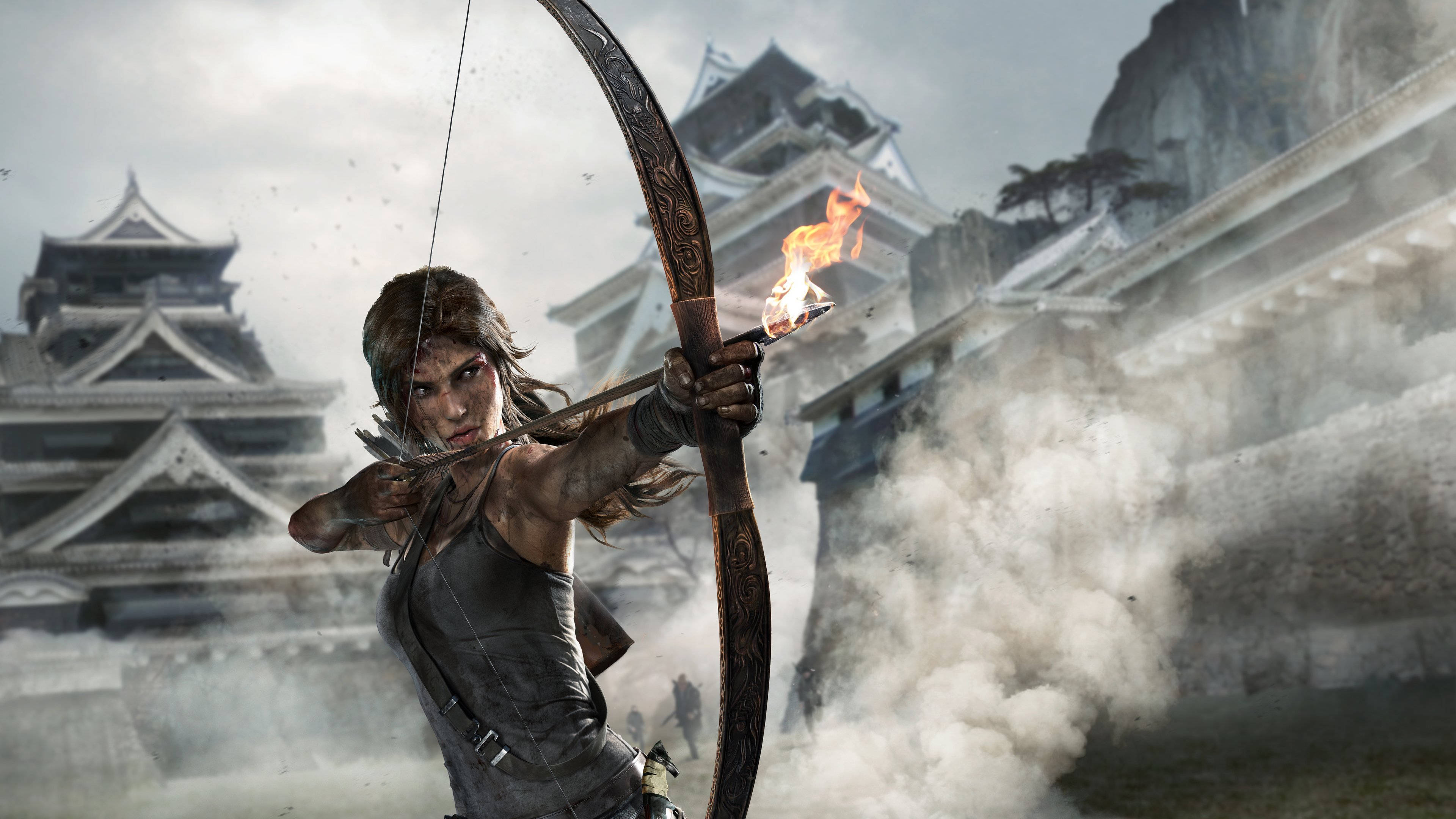 Tomb Raider Game 桌布 壁紙 — 一位兇猛的冒險家拉弓搭箭，箭上燃燒著火焰，背景是煙霧籠罩的古老日本城堡廢墟。