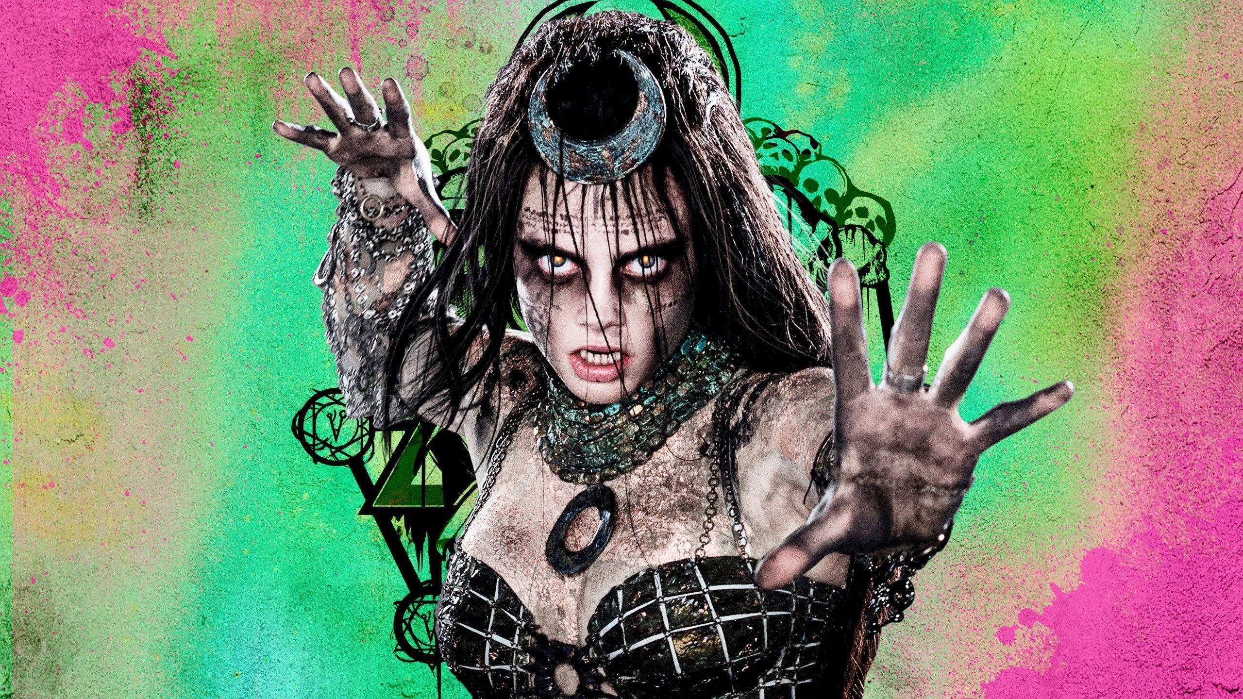 Enchantress 桌布 壁紙 — 一位兇猛的哥德女巫，眼睛發光，佩戴華麗珠寶，站在充滿活力的粉紅和綠色潑濺背景前。