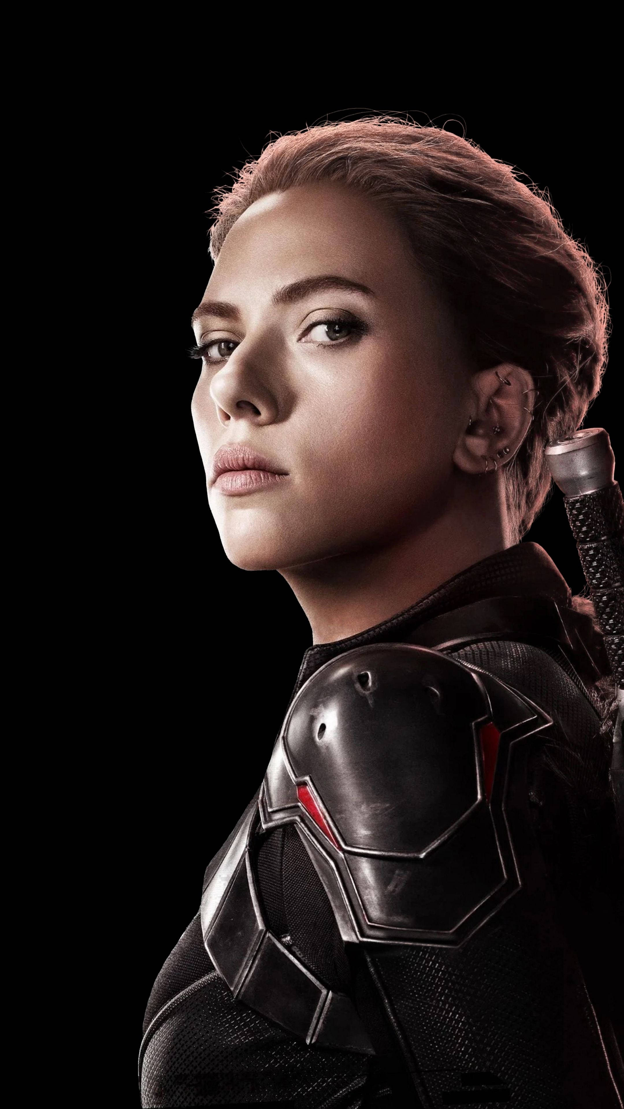 Scarlett Johansson Black Widow 桌布 壁紙 — 一位兇猛的女超級英雄身穿黑色戰術裝甲，帶有紅色點綴，在純黑背景下專注地凝視。
