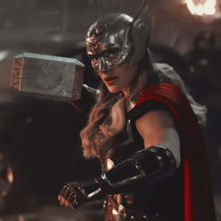 Jane Foster 桌布 壁紙 — 一位兇猛的女雷神穿著金屬盔甲，在昏暗的戰鬥場景中揮舞著她破裂的錘子。