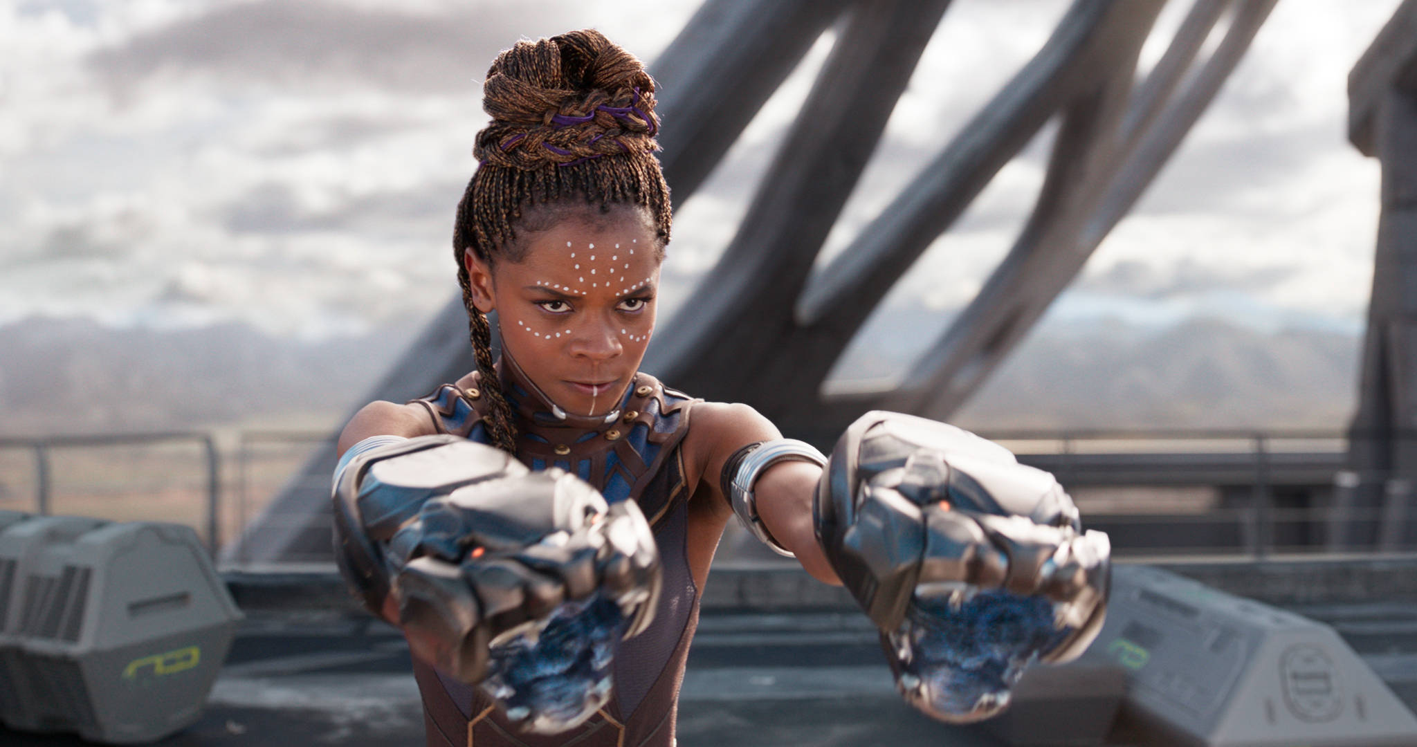 Wakanda 桌布 壁紙 — 一位兇猛的戰士，編著辮子，拳頭發光，站在未來風格的平台上，背景是陰天。