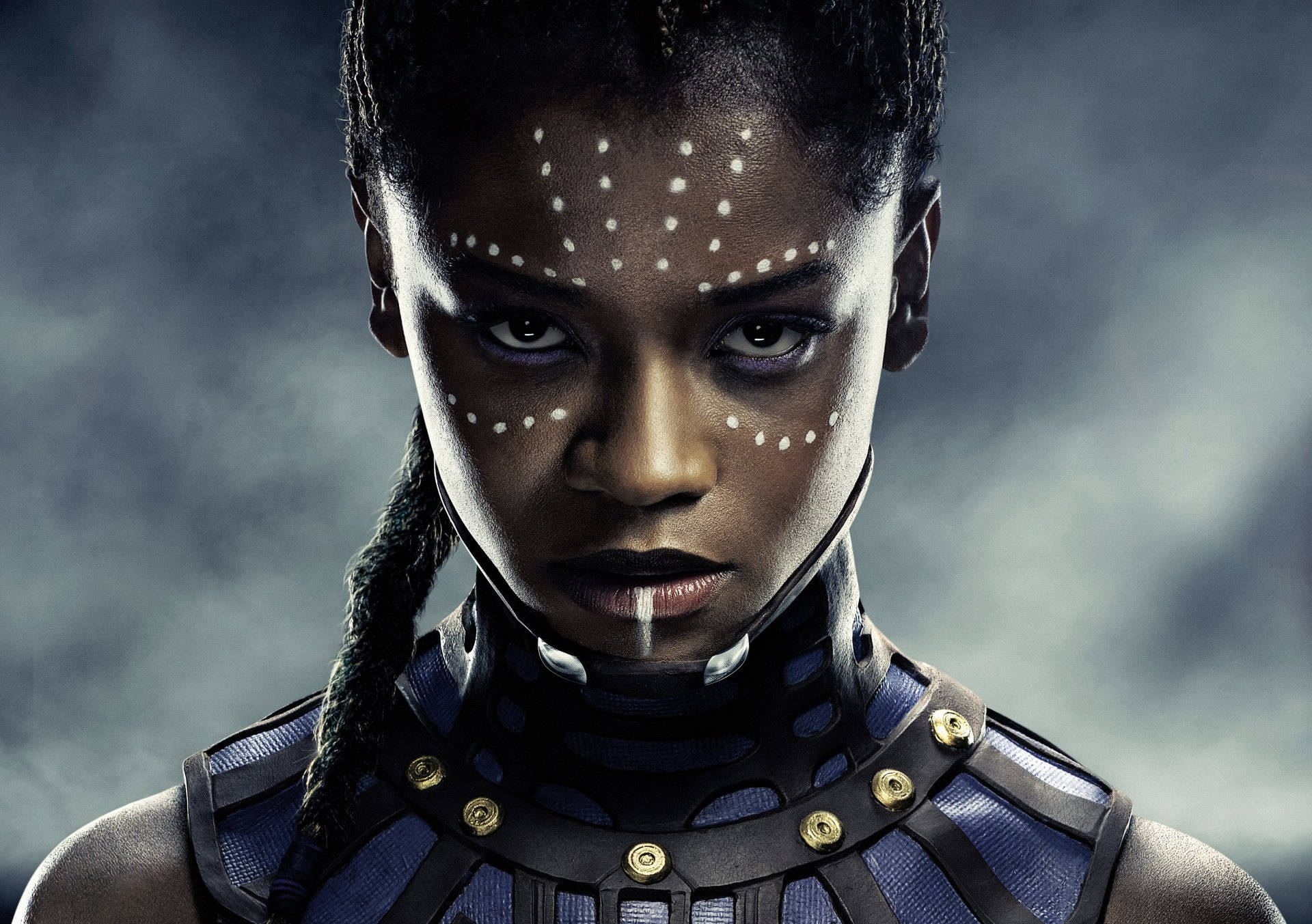Shuri 桌布 壁紙 — 一位兇猛的黑人女性，臉上帶有白色點點和辮子頭髮，在黑暗迷霧的背景中強烈凝視。