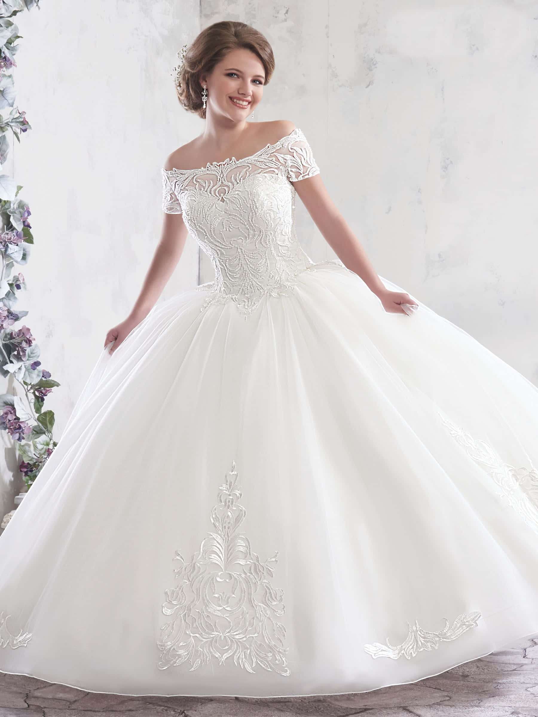Wedding Gown 桌布 壁紙 — 一位光彩奪目的新娘身穿白色露肩婚紗，帶有精緻蕾絲細節和蓬鬆薄紗裙，在花拱門旁優雅微笑。