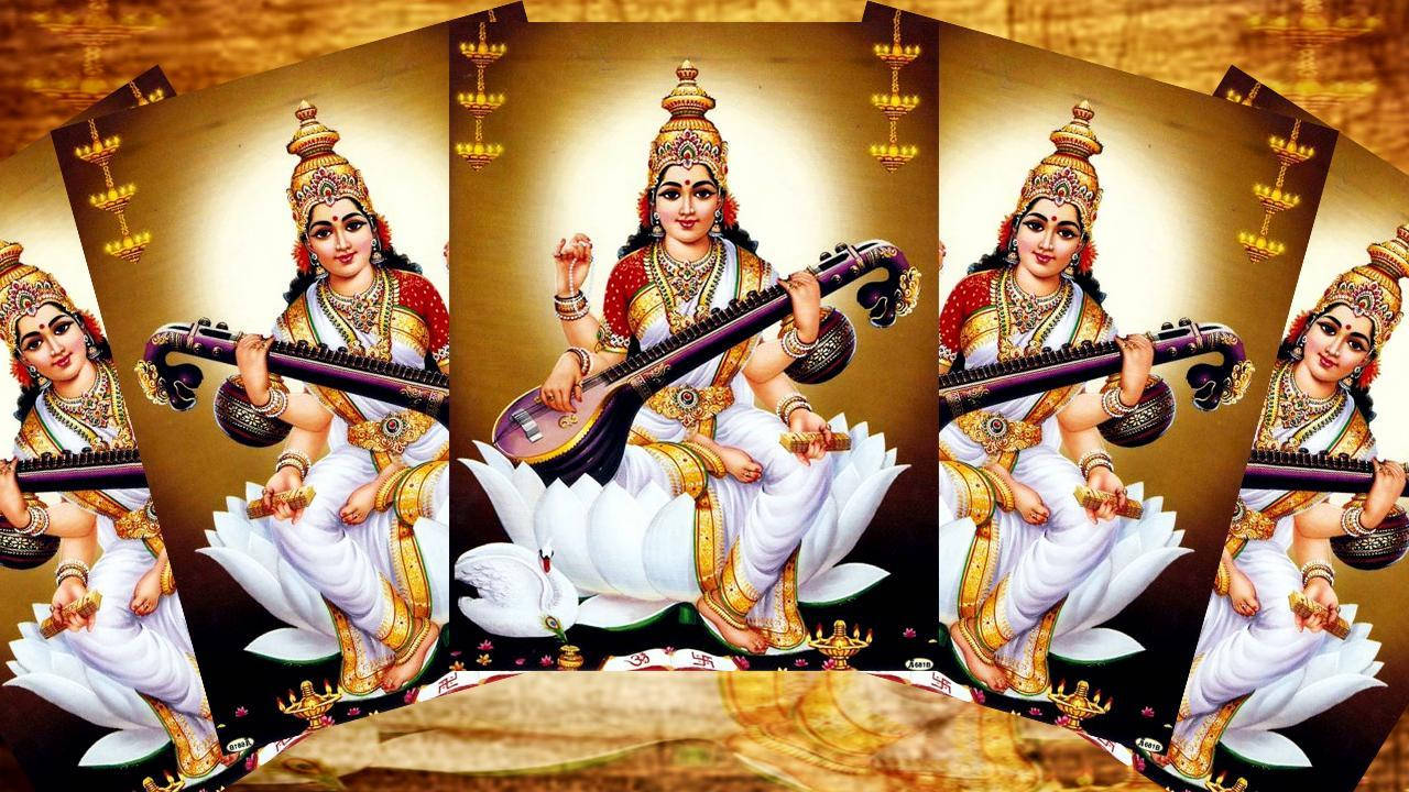 Saraswati Mata 桌布 壁紙 — 一位光彩照人的印度教女神優雅地坐在白色蓮花上，在金色背景下彈奏弦樂器。